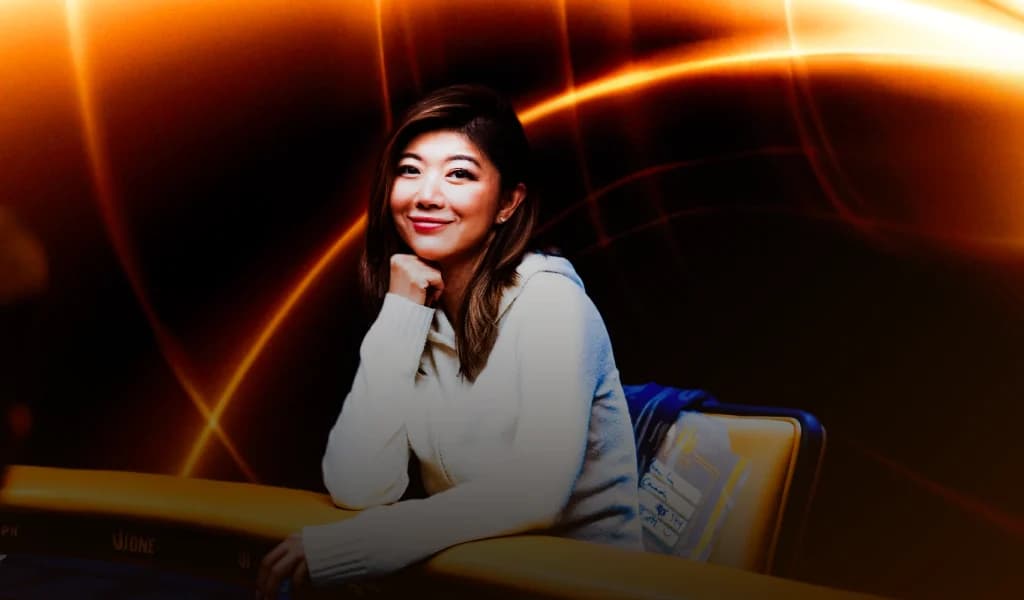 Poker pro Xuan Liu seated at a poker table, smiling with her chin resting on her hand.