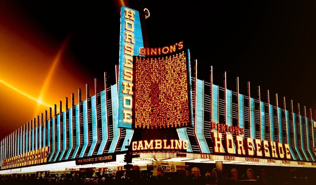 Night view of Binion's Horseshoe casino in Las Vegas, with bright neon signs lit up across the facade