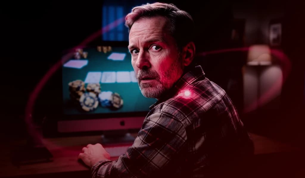 Man glances over his shoulder nervously while playing online poker.