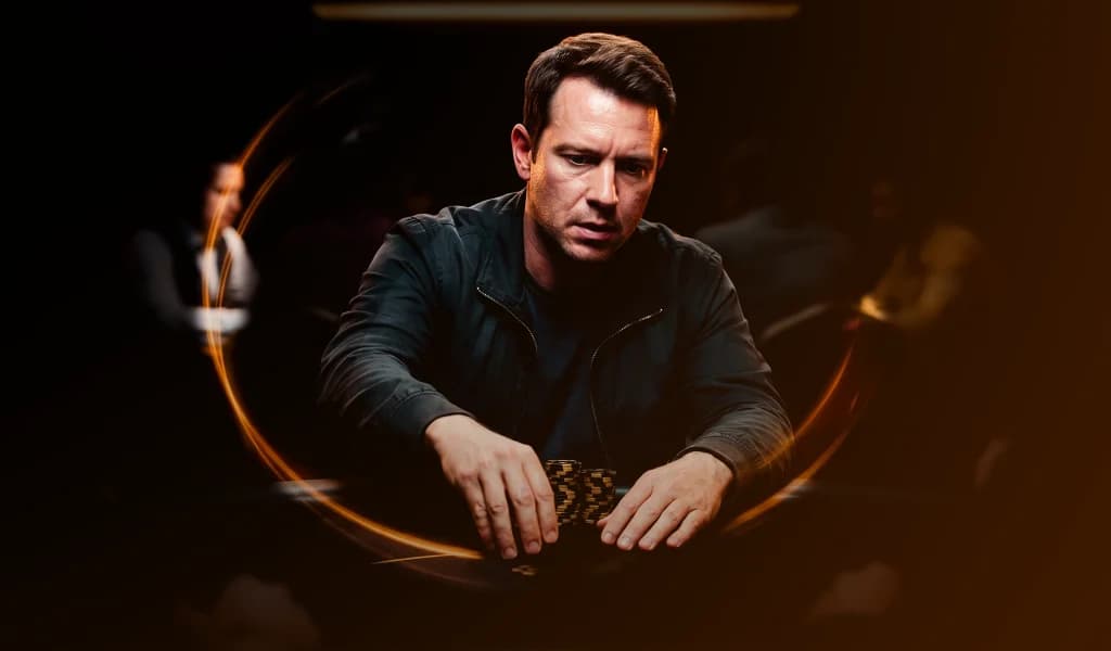 A composed poker player rests his hands near a small stack of chips, weighing his next move.