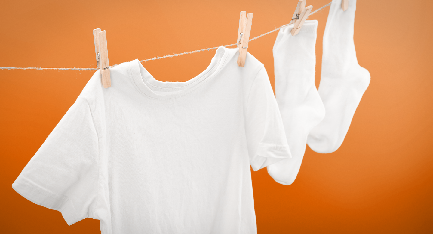 Bright & Clear white t-shirt & socks hanging from a line against a burnt orange background. 