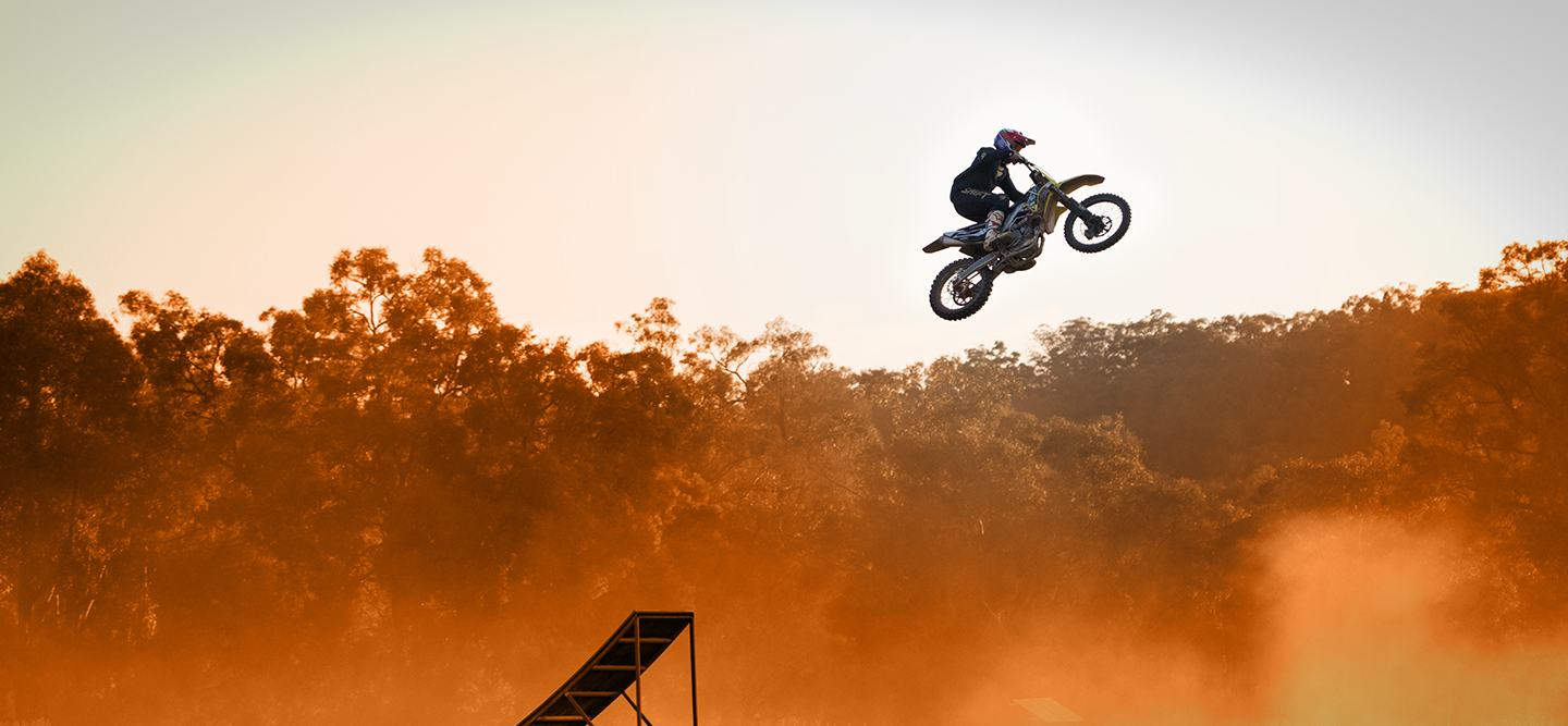 Man riding a bike of a platform in the midst of trees. 