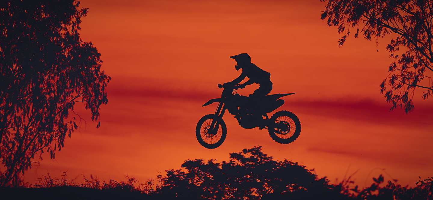 Silhouette of a man on a bike in the sky against the sunset.