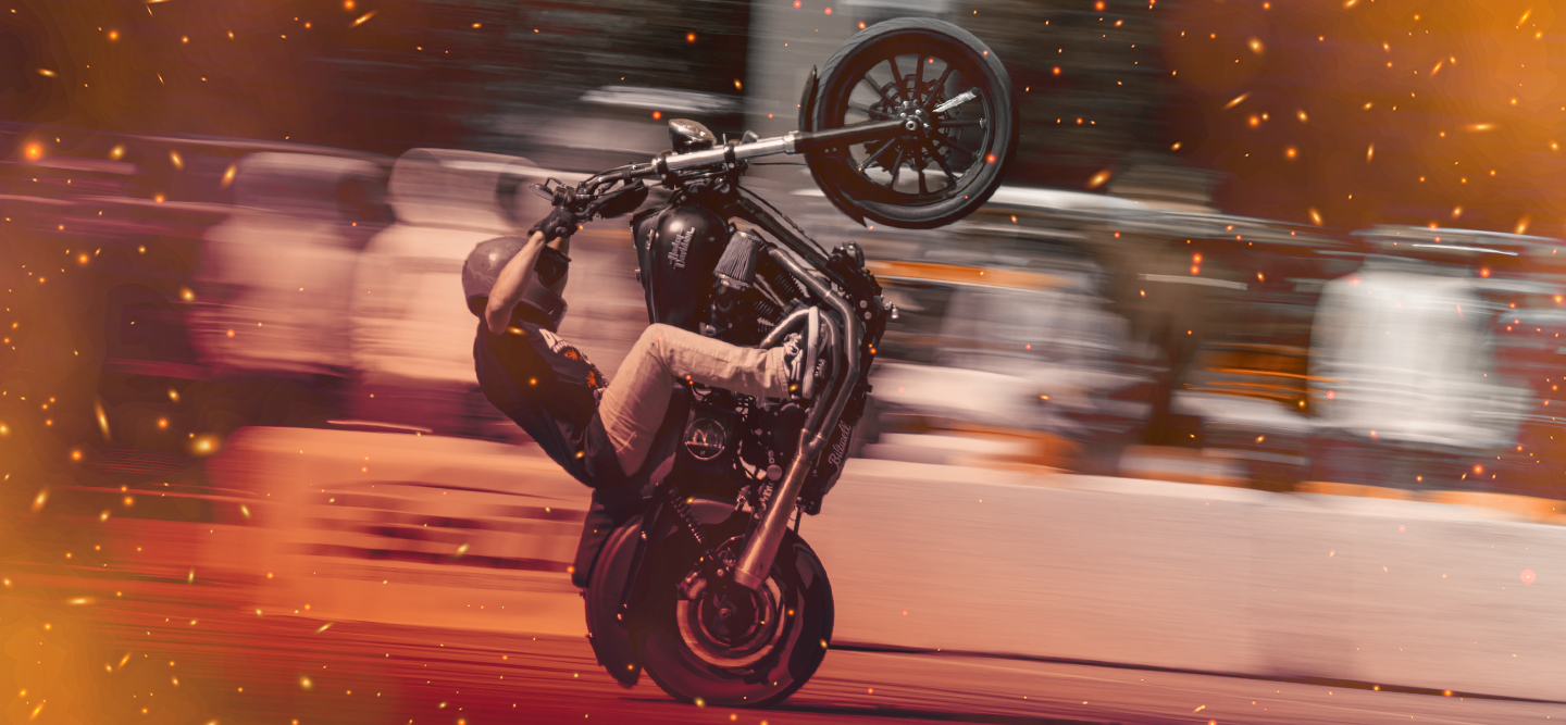 A driver doing a lifted bike stunt on a speed blurred background.