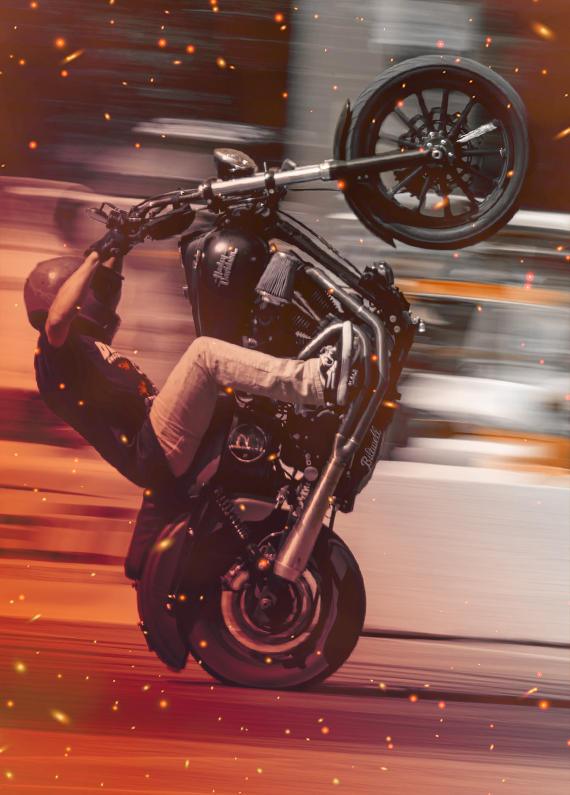 A driver doing a lifted bike stunt on a speed blurred background.