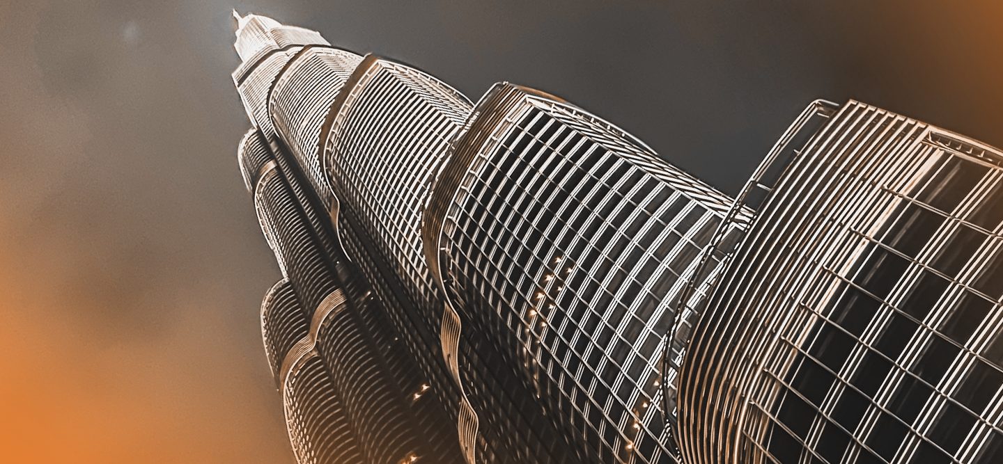 Steel high-rise building against dark orange and grey sky.