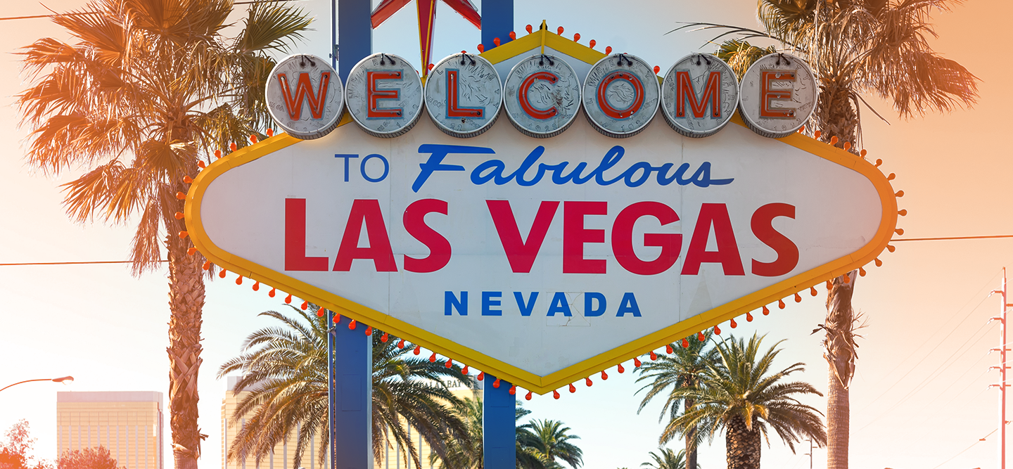 White sign captions ‘welcome to Las Vegas’ with a backdrop of palm trees.