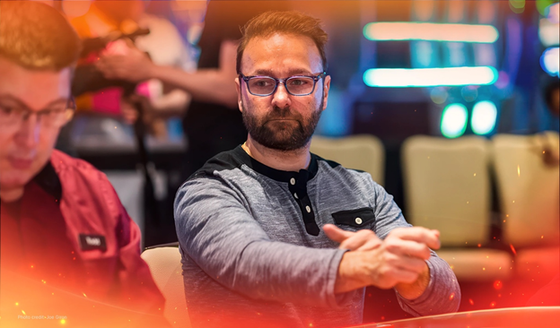 Daniel Negreanu focused at the poker table, wearing glasses and grey shirt.