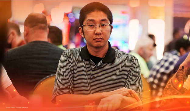 Christopher Nguyen seated at a poker table with chips, wearing a striped shirt in a busy casino setting