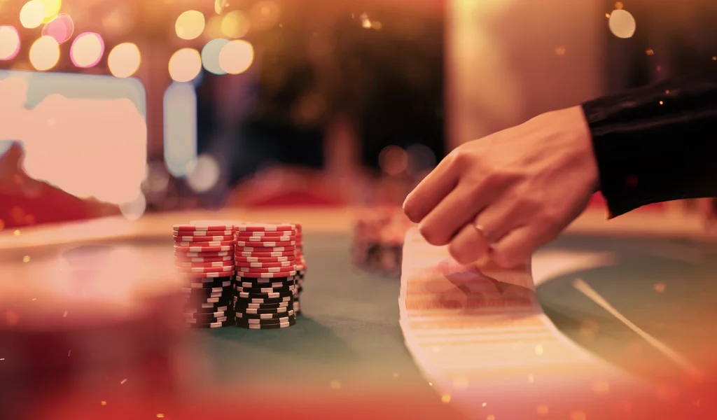Dealer spreads cards on a poker table with red and black chips stacked in front.