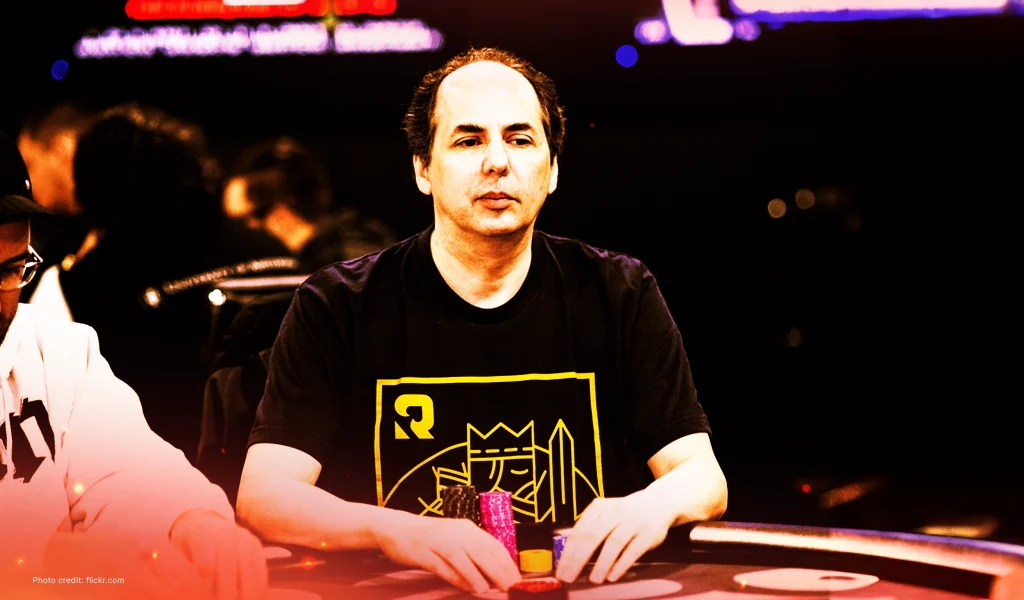 Allen Kessler seated at a poker table wearing a black T-shirt with a yellow graphic, holding colorful chips.