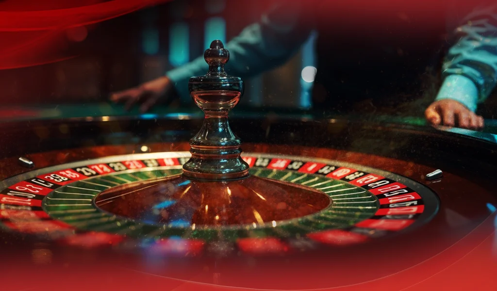 Roulette wheel spinning with players standing around the table in a casino setting.