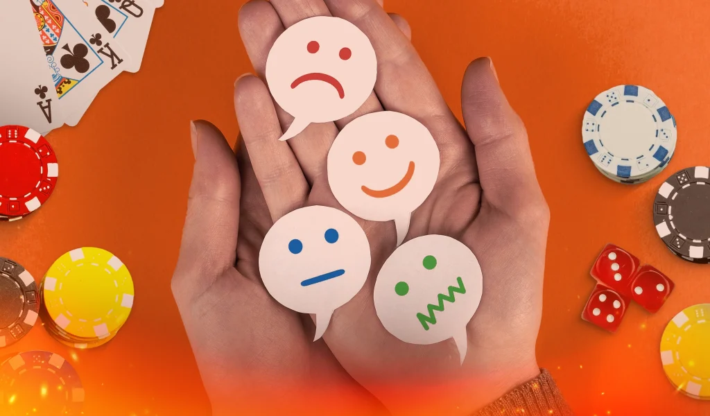 Hands holding paper cutouts of emotional faces with poker chips and cards in the background.