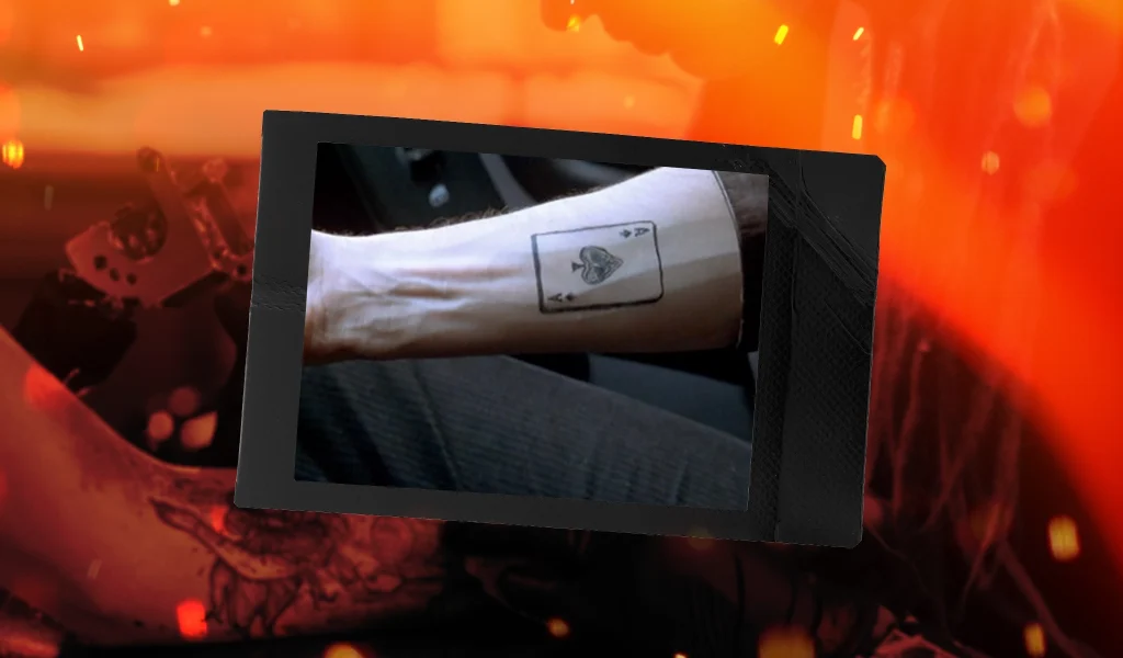 A simple forearm tattoo of an ace of spades playing card outlined in black ink.