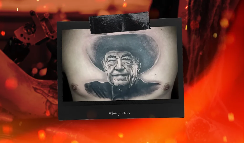A hyper-realistic black and grey tattoo of a man wearing a cowboy hat, inked across a person’s chest.