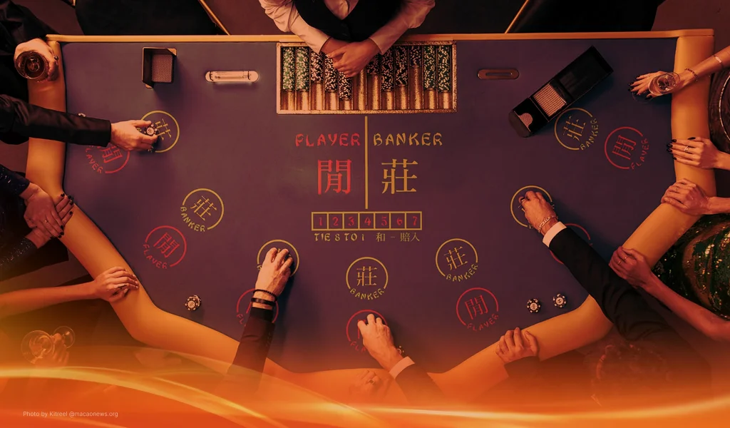 Overhead view of a baccarat table with players placing chips on player and banker sections.