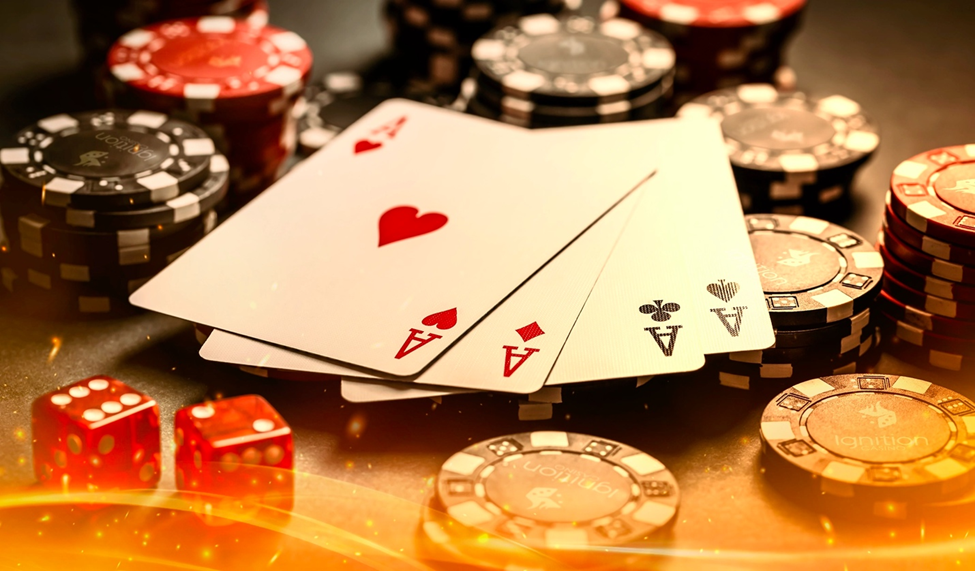 Four aces displayed on a poker table surrounded by Ignition-branded poker chips and red dice.
